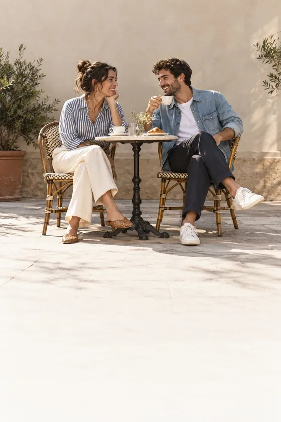Two friends talking at a cafe table in the sun